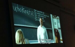 Bild från filmen Die Welle, lärare står vid en tavla, bakhuvud på elever syns