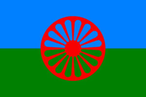 Romska flaggan som består av ett rött hjul mot en bakgrund där övre halvan är blå och nedre halvan är grön.