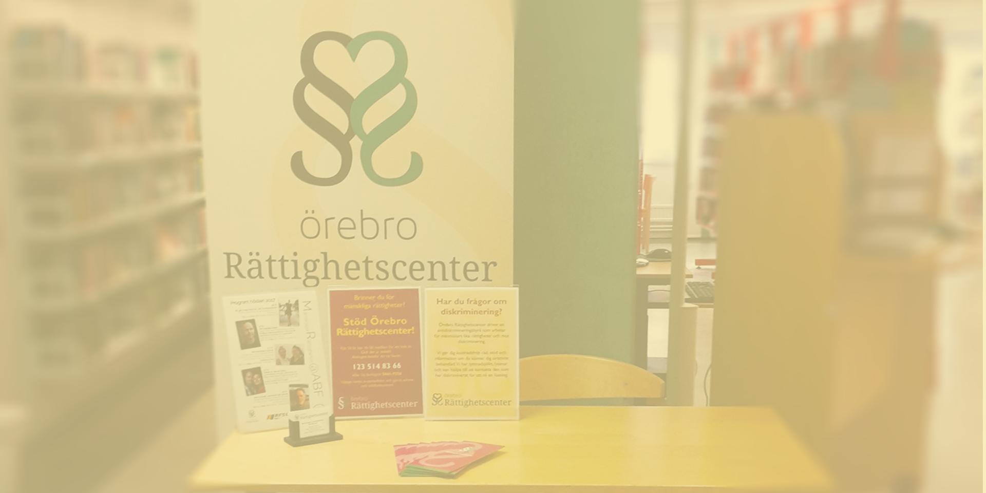 Biblioteksbesök gul Informationsbord med affischer och i bakgrunden syns en roll up med Örebro Rättighetscenters logga