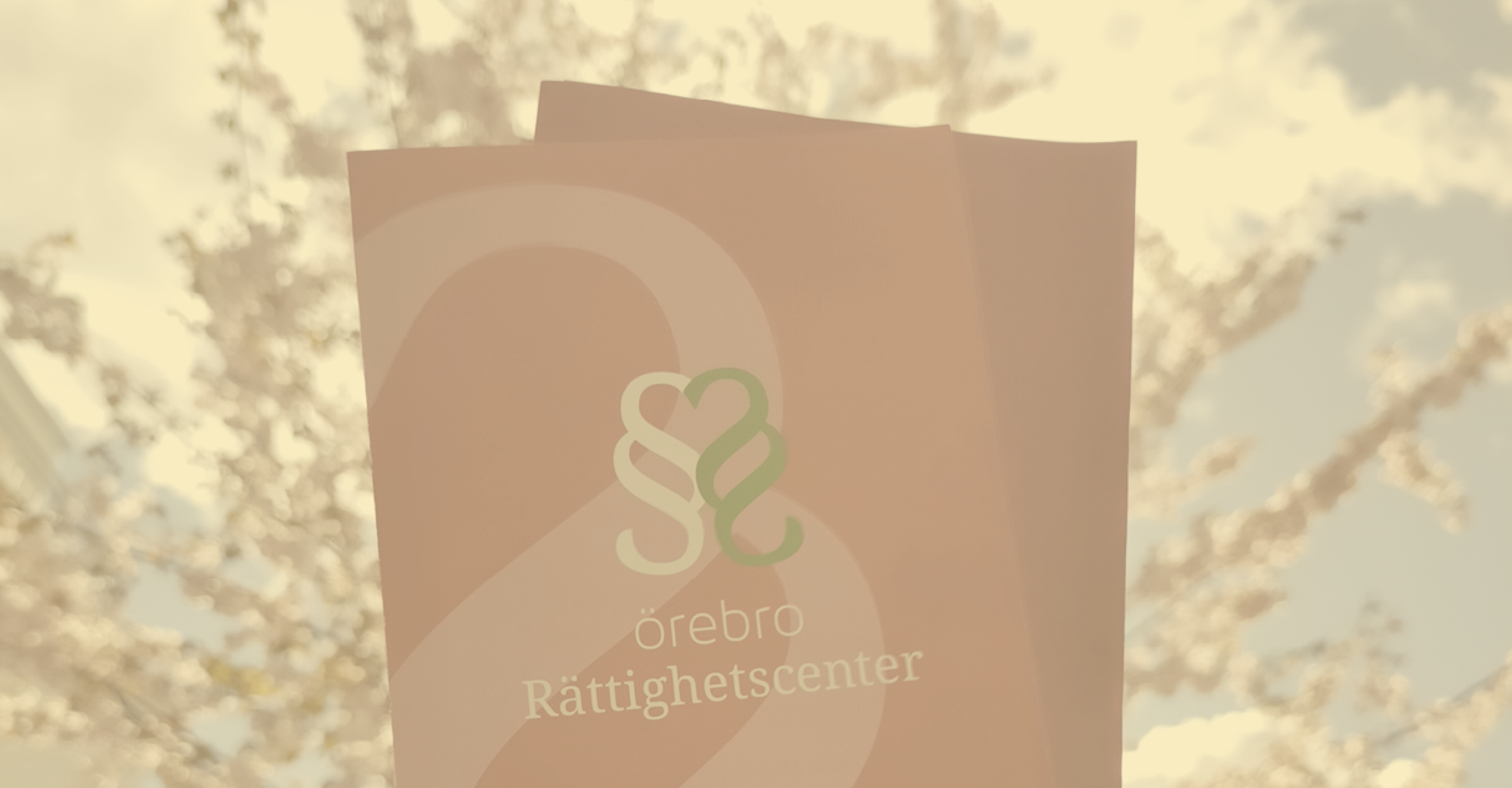 årsrapport 2024 Foldrar med Örebro Rättighetscenters logga mot en bakgrund med blomstrande träd.